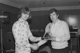 Un homme remettant un trophée à un autre homme lors de la ligue des Millionnaires