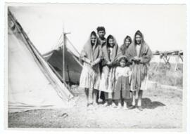 Un homme, trois femmes et une enfant Cris, près de tentes.