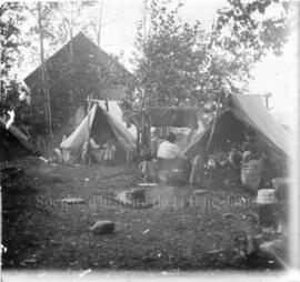 Campement d'une famille autochtone, près d'un bâtiment de bois