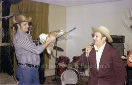 Un homme tenant un canard et un autre qui semble faire un discours lors d’une soirée western à Le...