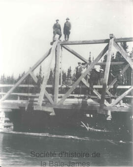 Deux hommes sur la tête d'un pont et cinq autres sur le pont