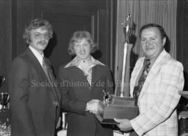 Trois hommes avec un trophée au banquet de clôture de la saison de la ligue Nordair