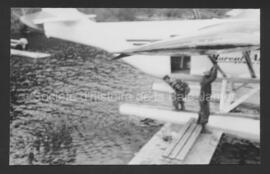 Joe Chibougamau tenant un avion Husky sur la quai du Rainbow Lodge.