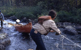 Bill Gunner and Sam, taking canoe up rapids, Testard Lake.